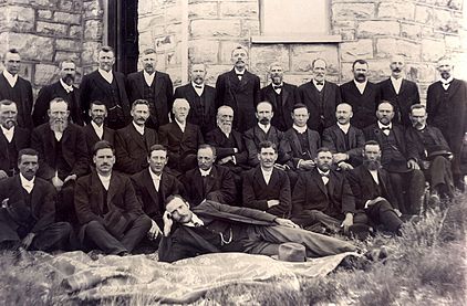 Die kerkraad van Postmasburg en besoekende predikante, onder andere dr. Casparus de Wet (eerste ry, tweede van links), J.G.H. van der Walt (eerste ry, vierde van links) en in die tweede ry vanaf vierde van links: Pieter Bingle, Taetse Hamersma, Martinus Postma, G.H.J. Kruger, Dirk Postma en J.H. Kruger, in 1918.