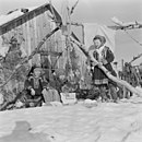 Barn i samedrakter med huskestativ av bjørkestokker. Foto fra Finnmark 1962. Foto: Billedbladet NÅ/Arkivverket