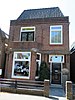 Nadrukkelijk vormgegeven woonhuis met bakstenen details, kenmerkend voor de bouwperiode, schilddak met plat.