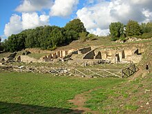 Photographie représentant les vestiges des thermes de Roselle sur les flancs d'une bute boisée.