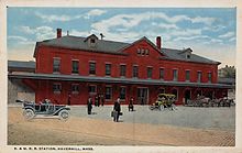 A postcard of a two-story brick railway station