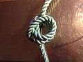 Step 4 of tying Cross constrictor knot: the far side loop folded over the simple knot