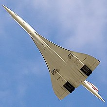 A view from below of an aeroplane in flight, with a slender fuselage and swept back wings.