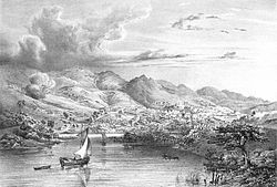 Engraving depicting two small boats sailing into a bay backed by high mountains at the foot of which are the buildings of a town