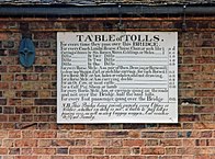 Antique table of bridge tolls now displayed on the outside of the toll house. Tolls range from a halfpenny for a pedestrian to two shillings for a large coach