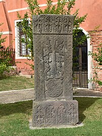 Stèle en pierre grise sculptée d'une croix et de fins ornements.