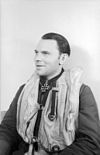 Smiling man wearing life jacket and a military decoration in shape of an Iron Cross at his neck.