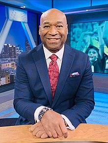 Ellerson sitting in a studio wearing a suit and tie