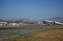 A plane on the tarmac of an airport with a mountainous horizon