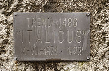 Image d'une plaque couleur bronze gravée d'un texte, fixée sur un mur.