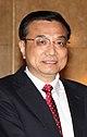 a smiling man with a short haircut, wearing glasses, a white shirt, a suit and a red tie