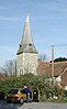 A shingled broach spire on a flint tower