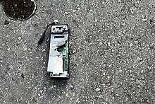 An exploded device is on the ground with its components visible.