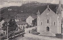 Photo depuis une hauteur d'une pace de village avec le porche de l'église et un tramway.