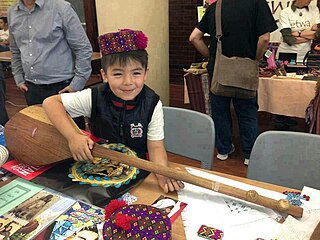 Hazara boy in cultural clothing with a dambura