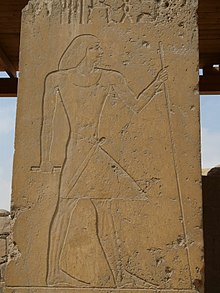 Relief of a man standing holding a staff