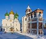 An orthodox church with green and golden domes and a building in red brick