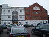 A red-brick gabled building on the right, with a flat-roofed grey block to the left