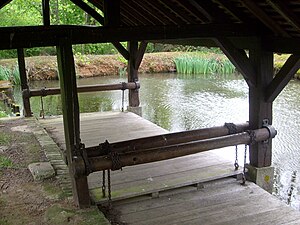 Photographie en couleurs d'un plancher et d'une toiture en bois surplombant un plan d'eau.