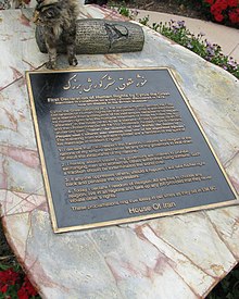 Monument consisting of a bronze plaque fixed to a sloping marble slab, with a bronze replica of the Cyrus Cylinder above the plaque.