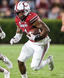 Lloyd rushing the football on a field in college