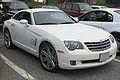 Une voiture blanche 2 portes vue de l'avant droit sur un parking aux côtés d'autres voitures.