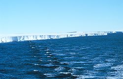 Dark sea in the foreground extends to a long ice ridge that stretches across the picture