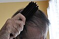 ヘアブラシで頭髪を手入れする男性の図