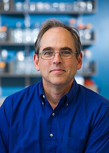 <headshot of Peter Sorger circa 2014 wearing glasses and blue button-down shirt>