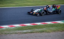 White, black and orange Formula One car turning left