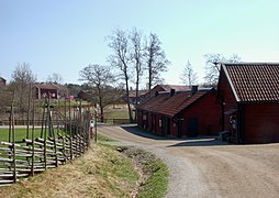 Photo de la rue d'un village avec, des bâtiments d'un côté et des clôtures, de l'autre.