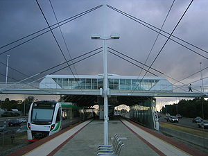 Train station island platform with a footbridge and large shelter