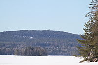 Åmänningen is covered in snow and ice. Landsberget is visible in the background. The picture is taken from Halvarsviken.