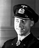 A smiling man with a black uniform and peaked cap.