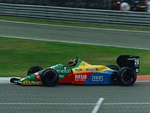 Photo d'une monoplace rouge, verte et jaune sur un circuit.