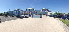 wide panoramic view taken from footway linking car park towards main buildings on a sunny day against a blue sky