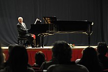 Hicks playing a grand piano onstage