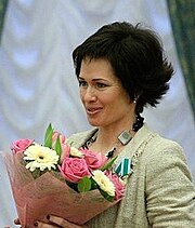 Photographie d'une femme brune portant un bouquet de fleurs.