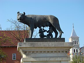 Statuia „Lupa Capitolina" (detaliu). În spate Biserica romano-catolică „Adormirea Maicii Domnului”