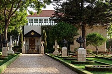 Stone pathway surrounded by gardens leading to a building with golden gates.