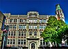 Fascade of a four storey building in perpendicular Gothic style in front of a blue sky.