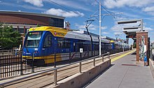 Yellow and blue light rail train at a stop