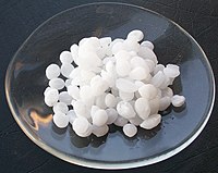 Sample of sodium hydroxide as pellets in a watchglass