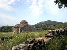 photographie : une petite église à dôme en tuiles dans une prairie fleurie