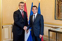 Valls is shaking hands with Orešković in front of their respective country's flags.