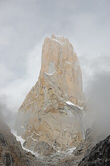 Pic montagneux, entouré par une vague de brume, saupoudré de neige