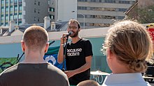 Sriranganathan speaking to a crowd outside Queens Wharf, Brisbane