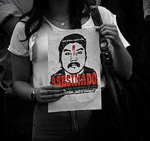 Protestor holding sign showing a drawn image Catrillanca with a gunshot wound in his forehead.