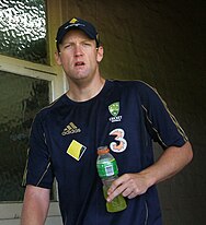 A man wearing Australian training shirt holding a bottle