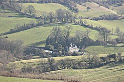 Large house nestling amongst trees and fields